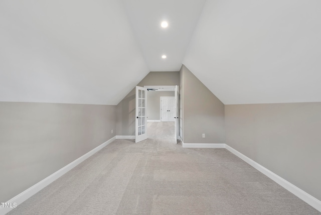 additional living space with french doors, light colored carpet, and lofted ceiling