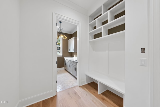 mudroom featuring crown molding, light hardwood / wood-style flooring, and a notable chandelier