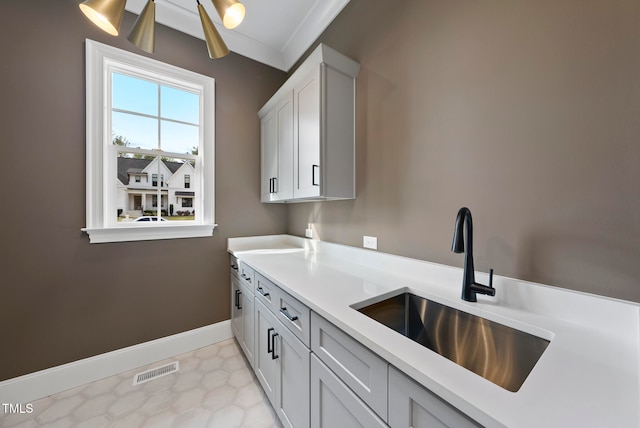 laundry room featuring sink, light tile patterned floors, and ornamental molding