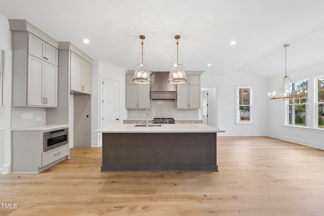 kitchen featuring lofted ceiling, hanging light fixtures, and light hardwood / wood-style flooring