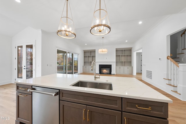 kitchen featuring decorative light fixtures, light stone countertops, sink, and light hardwood / wood-style flooring