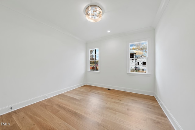 empty room featuring ornamental molding, light wood-type flooring, and a healthy amount of sunlight