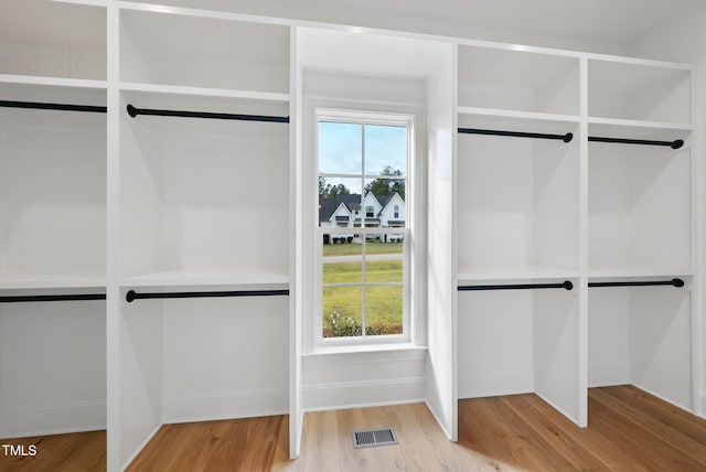 walk in closet with light hardwood / wood-style flooring