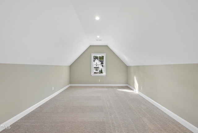 bonus room with light colored carpet and lofted ceiling