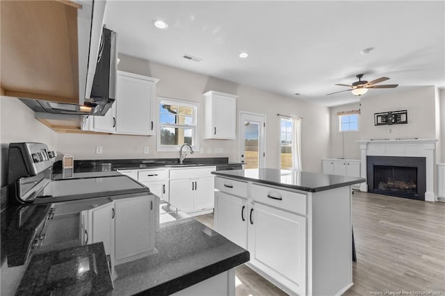 kitchen featuring white cabinetry, a center island, ceiling fan, and sink