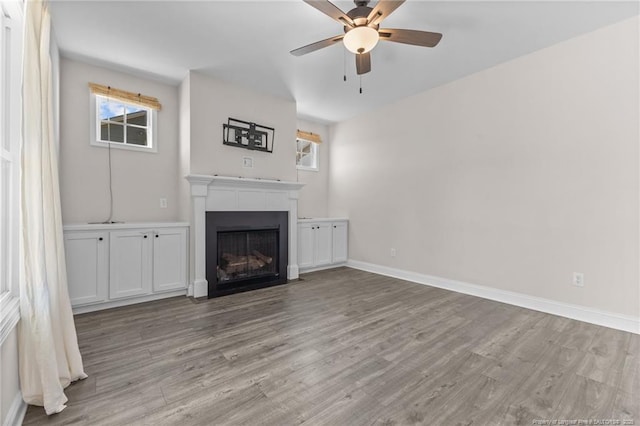 unfurnished living room with light wood-type flooring, a wealth of natural light, and ceiling fan