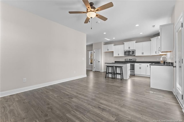 kitchen featuring a kitchen breakfast bar, ceiling fan, a kitchen island, white cabinetry, and stainless steel appliances