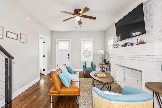 sitting room featuring ceiling fan, dark wood-type flooring, and a brick fireplace