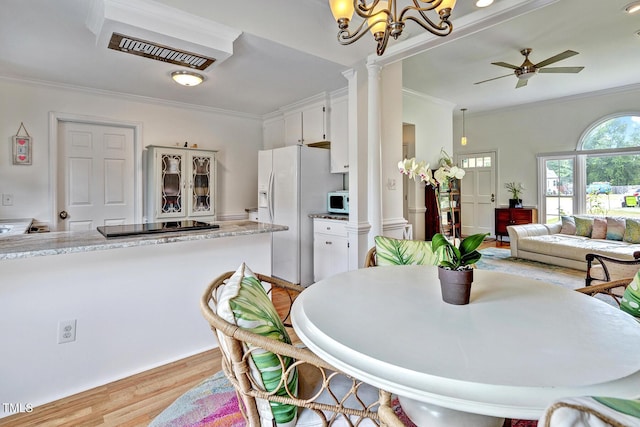 dining space featuring ceiling fan with notable chandelier, light hardwood / wood-style floors, ornate columns, and ornamental molding