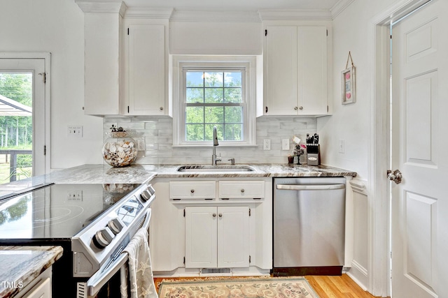 kitchen with appliances with stainless steel finishes, light stone counters, white cabinetry, and sink