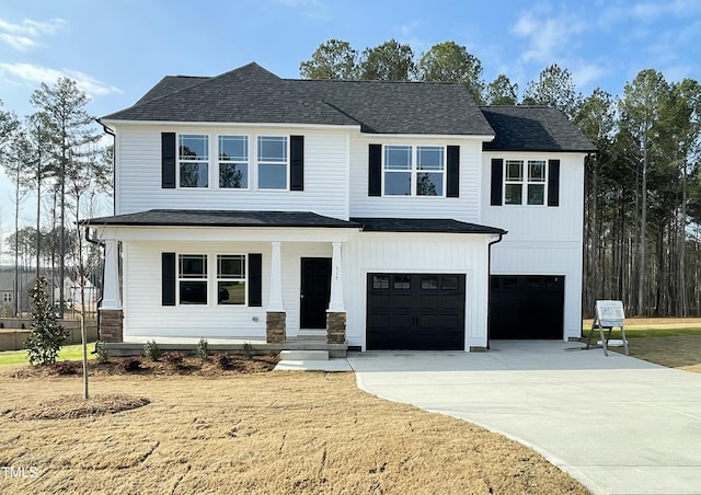 view of front of home with a front yard, covered porch, and a garage