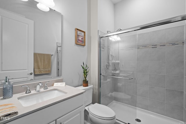 bathroom featuring toilet, a shower stall, and vanity