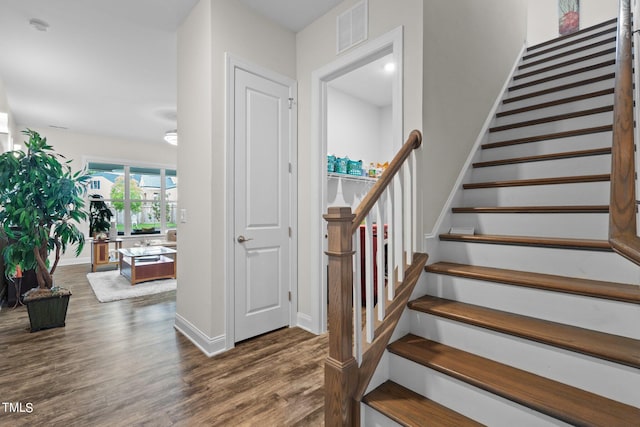 stairway with baseboards, visible vents, and wood finished floors