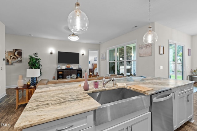 kitchen featuring stainless steel dishwasher, dark wood-type flooring, open floor plan, a sink, and light stone countertops