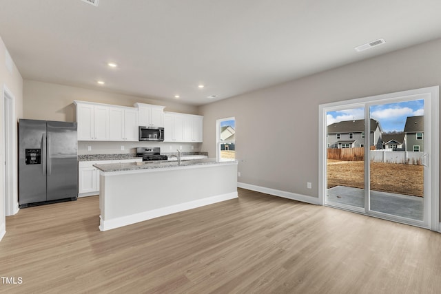 kitchen with white cabinetry, appliances with stainless steel finishes, an island with sink, and light wood-type flooring