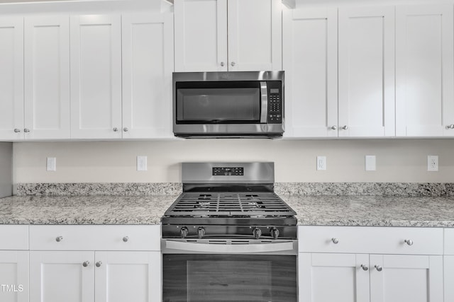 kitchen featuring white cabinets, light stone countertops, and range with gas stovetop