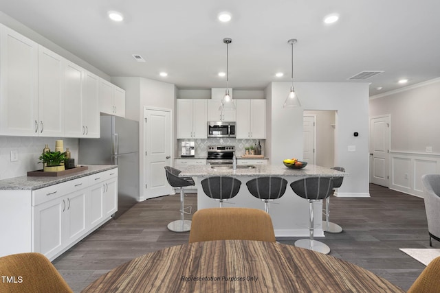 8816 Melvin St Unit 15-, Smithfield, Willow Springs, NC 27592 - kitchen with stainless steel appliances, a breakfast bar, backsplash, white cabinetry, and a kitchen island with sink