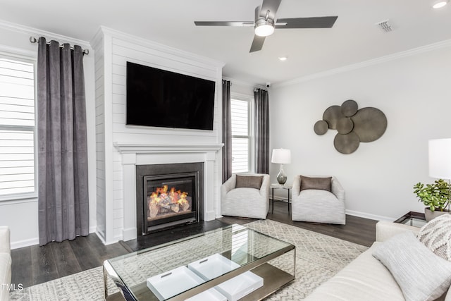 living area with a fireplace, crown molding, visible vents, wood finished floors, and baseboards