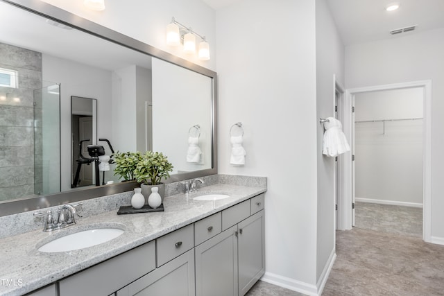 bathroom with a walk in closet, visible vents, a sink, and double vanity