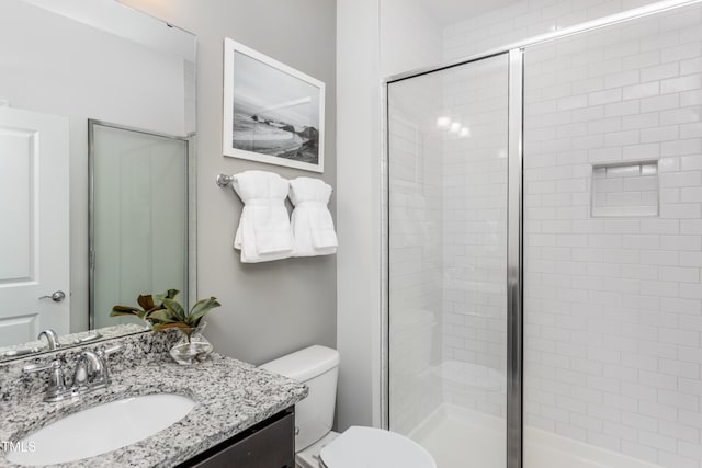 bathroom featuring toilet, a stall shower, and vanity