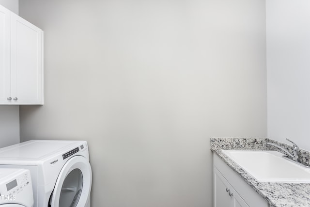 laundry room with cabinet space, washing machine and dryer, and a sink