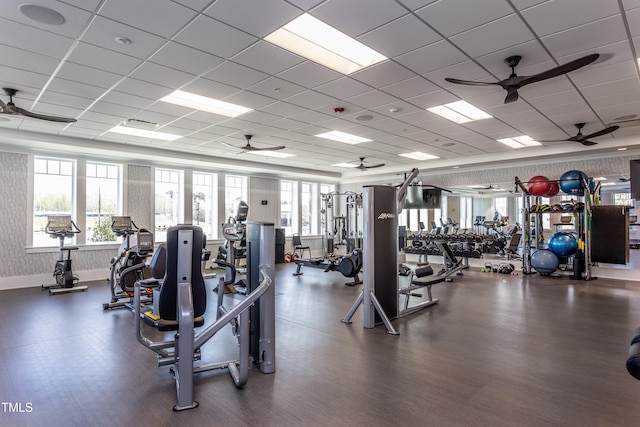 workout area featuring a paneled ceiling, ceiling fan, and baseboards