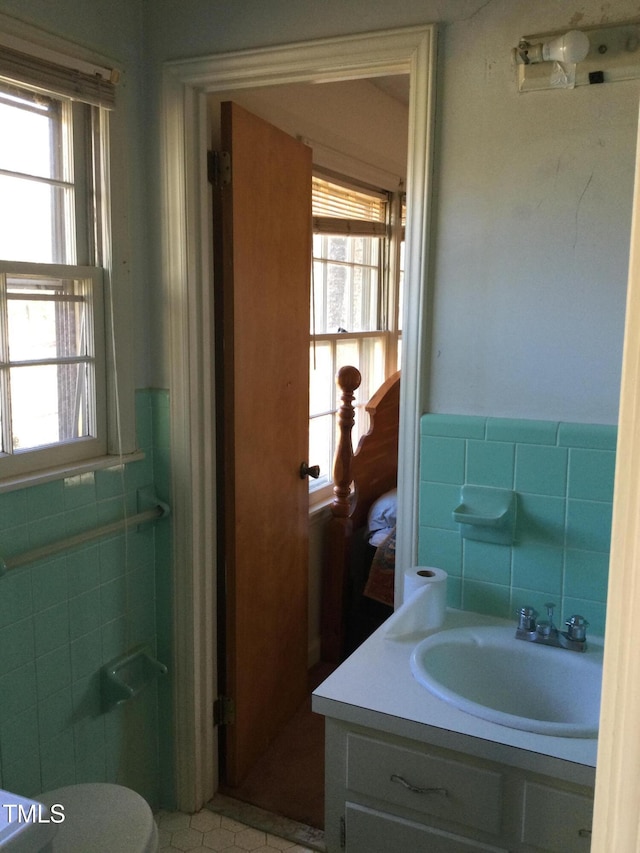 bathroom featuring vanity, tile walls, and toilet