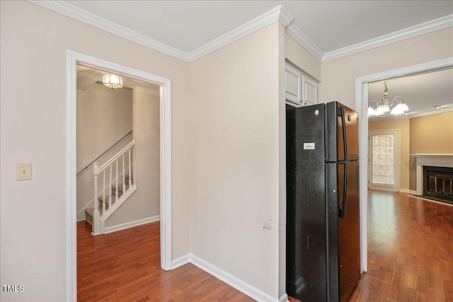 kitchen with a chandelier, crown molding, black refrigerator, and dark wood-type flooring