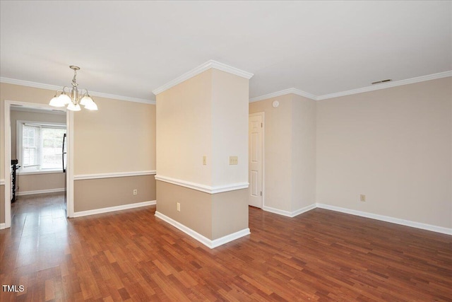 spare room with crown molding, dark hardwood / wood-style flooring, and an inviting chandelier