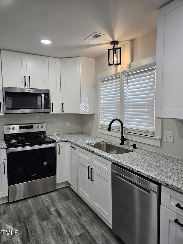 kitchen featuring white cabinetry, sink, light stone counters, dark hardwood / wood-style floors, and appliances with stainless steel finishes