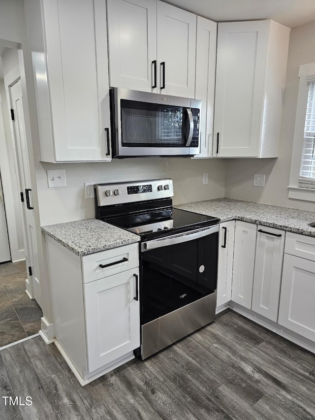 kitchen with appliances with stainless steel finishes, dark hardwood / wood-style floors, white cabinetry, and light stone counters