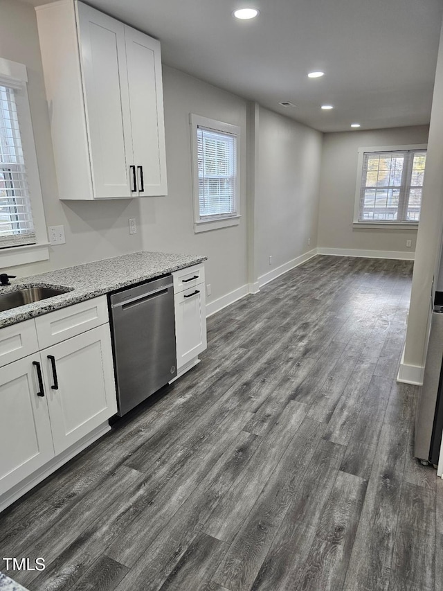 kitchen with dark hardwood / wood-style flooring, stainless steel dishwasher, light stone counters, sink, and white cabinetry