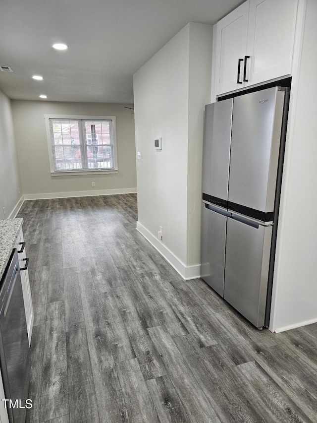 interior space with white cabinets, light stone counters, hardwood / wood-style floors, and appliances with stainless steel finishes