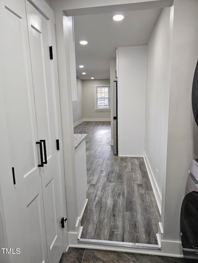 corridor with dark hardwood / wood-style floors and stacked washer / drying machine