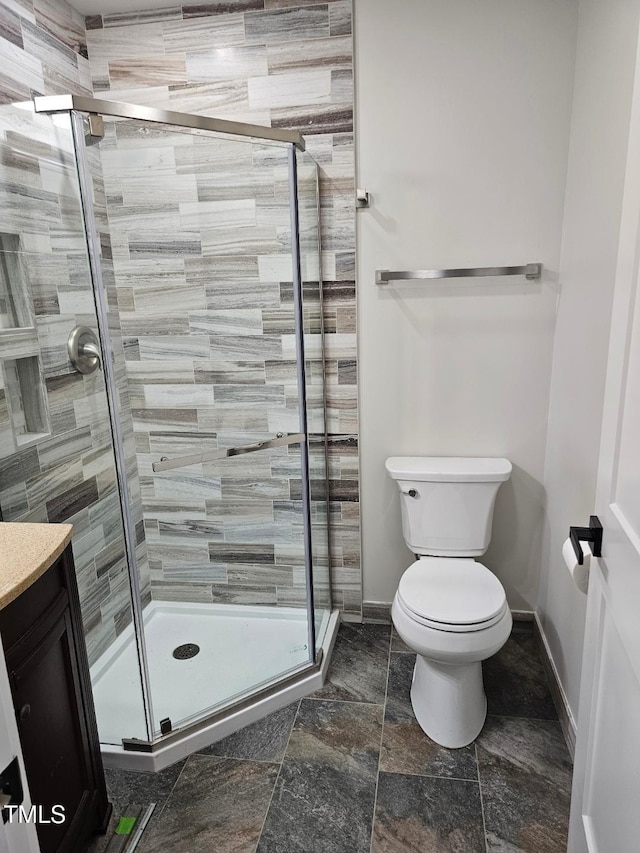 bathroom featuring a shower with door, vanity, and toilet