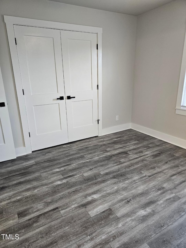 unfurnished bedroom with dark hardwood / wood-style floors and a closet