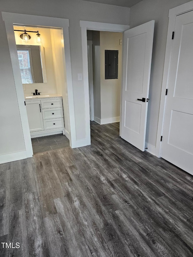 unfurnished bedroom with sink, dark hardwood / wood-style flooring, ensuite bathroom, and electric panel