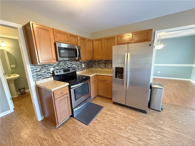 kitchen featuring tasteful backsplash, light hardwood / wood-style flooring, and appliances with stainless steel finishes