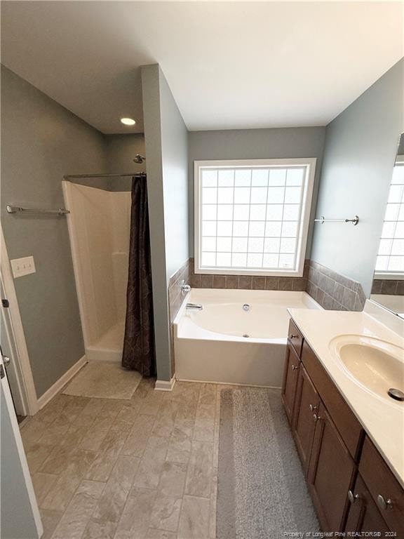 bathroom featuring plenty of natural light, separate shower and tub, and vanity