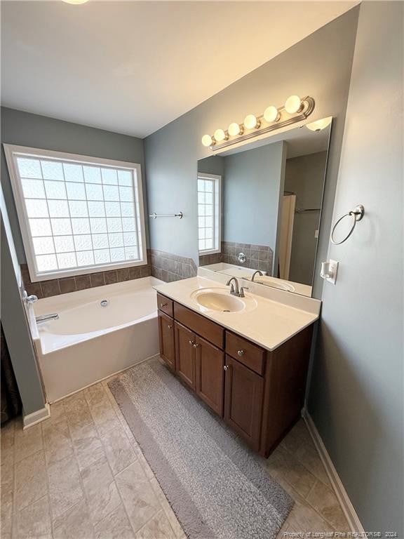 bathroom featuring plenty of natural light, vanity, and a bath