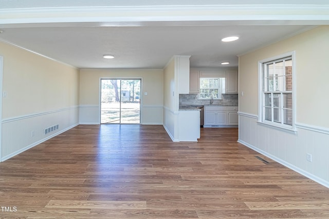 unfurnished living room with crown molding, sink, and wood-type flooring