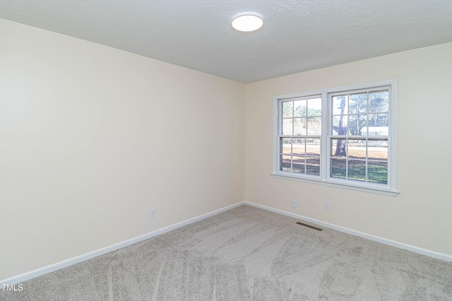 carpeted empty room featuring a textured ceiling