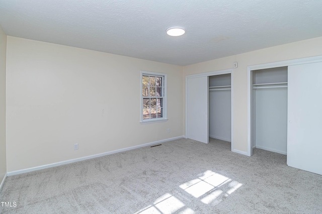 unfurnished bedroom with light carpet and a textured ceiling