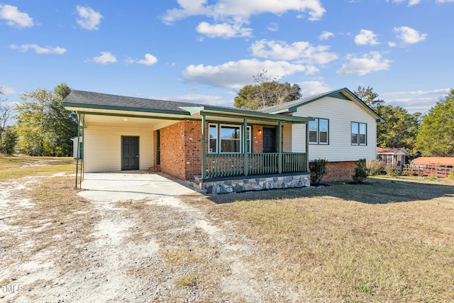 ranch-style house featuring covered porch, a front lawn, and a carport