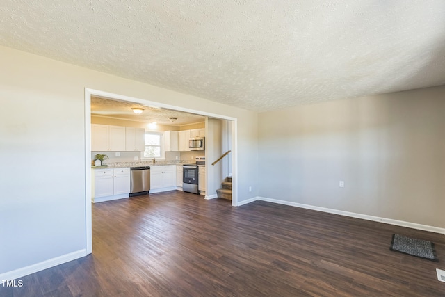 unfurnished living room with dark hardwood / wood-style flooring and a textured ceiling