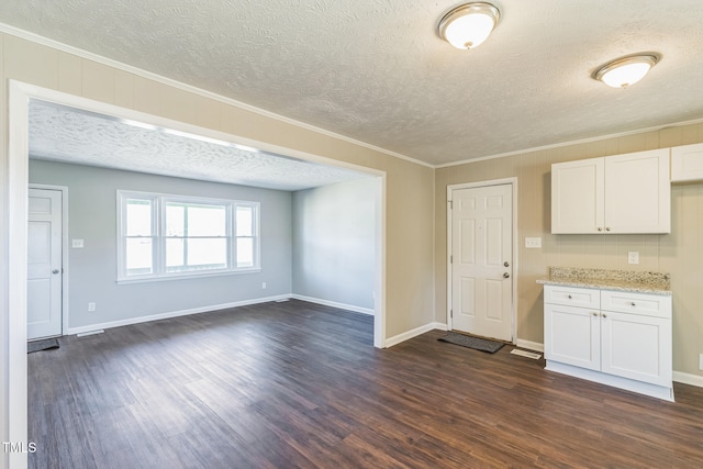 kitchen with white cabinets, a textured ceiling, dark hardwood / wood-style floors, and ornamental molding