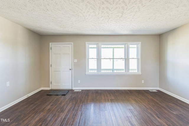 spare room featuring a textured ceiling and dark wood-type flooring