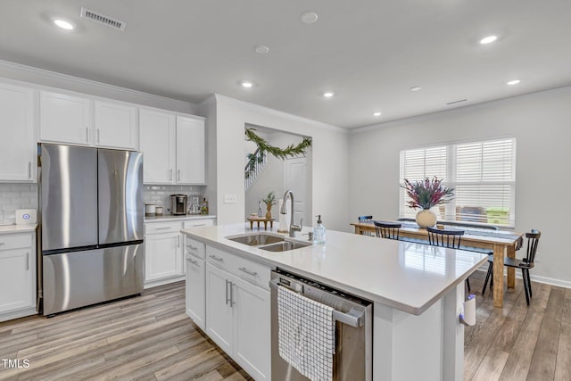 kitchen with white cabinets, light wood-type flooring, stainless steel appliances, and tasteful backsplash