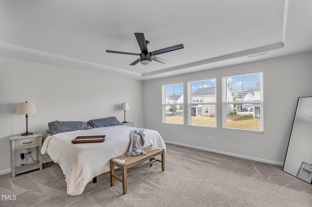 carpeted bedroom featuring ceiling fan and a raised ceiling