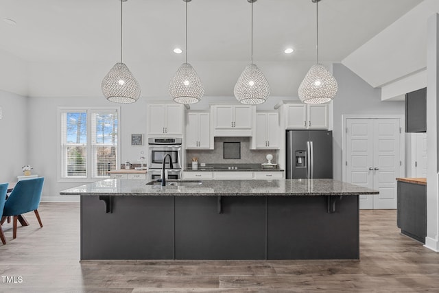 kitchen featuring white cabinetry, decorative light fixtures, stainless steel appliances, and dark stone countertops